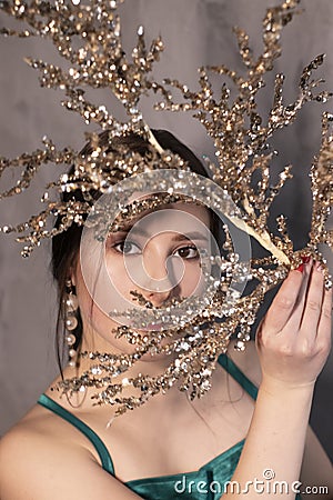 Sexy attractive brunette woman in elegant green aquamarine dress with artificial branch with sparkly sequins. beautiful sensual Stock Photo