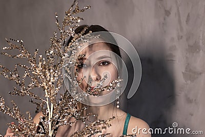 Sexy attractive brunette woman in elegant green aquamarine dress with artificial branch with sparkly sequins. beautiful sensual Stock Photo
