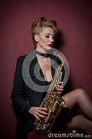attractive woman with saxophone posing on red background. Young sensual blonde playing sax. Musical instrument, jazz Stock Photo
