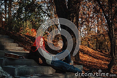 Sexy beautiful redhead girl with magnificent long hair. Ukulele playing, sitting on the steps in the park. Perfect woman portrait Stock Photo