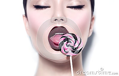 beauty girl eating lollipop. Glamour model woman licking sweet colorful lollipop candy Stock Photo