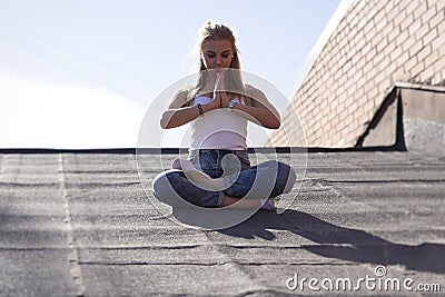 Sexy blonde girl meditates in solitude on the roof on a sunny day Stock Photo