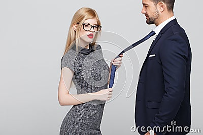 blonde manipulator woman pulling man by tie Stock Photo