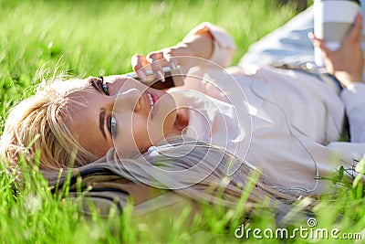 Sexy blonde woman talking on the mobile phone and lying on meadow Stock Photo