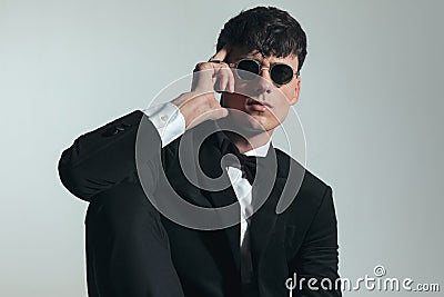 sexy fashion man in black tuxedo touching temple with fingers Stock Photo
