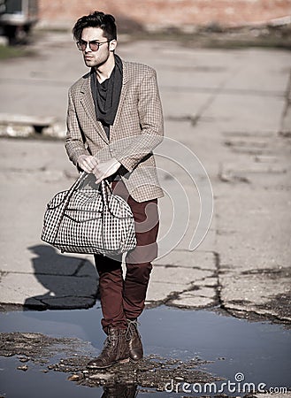 fashion man model dressed vintage elegant holding a bag posing outdoor Stock Photo