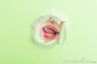 female mouth wearing lipstick thru ripped paper hole Stock Photo