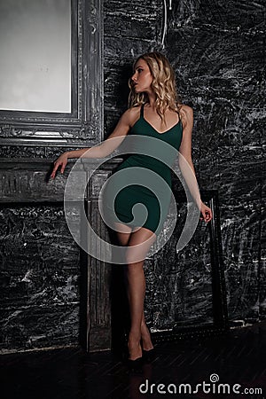 Sexy fit blod model with long legs in high heels posing in fashion dreen dress on dark dramatic Gothic background in dark shadow Stock Photo