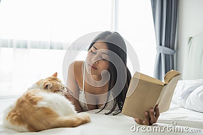 girl with cat read book on bed Stock Photo