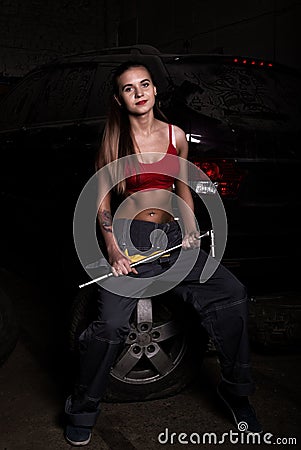 girl mechanic sitting on a tire holding a wrench in his hand. colorless life concept Stock Photo