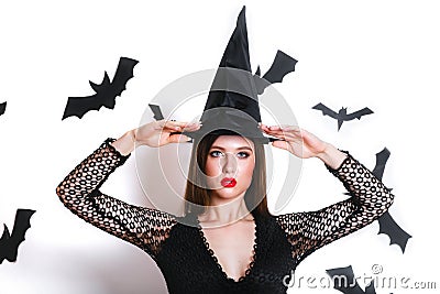 Happy gothic young woman in witch halloween costume with hat standing and smiling over white background Stock Photo