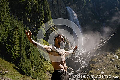 Sexy man in Alps waterfall. Man freedom lifestyle in nature. Hispanic man summer on nature. Calmness and relax in nature Stock Photo