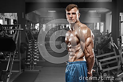 muscular man posing in gym, shaped abdominal, showing triceps. Strong male naked torso abs, working out Stock Photo