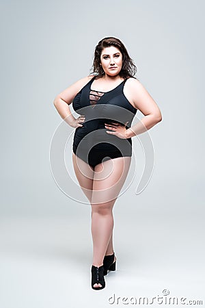 Sexy plus size fashion model in black one-piece swimsuit, fat woman in lingerie on gray background Stock Photo