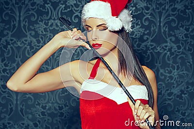 santa woman with red lips posing indoor with whip at Christ Stock Photo