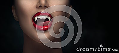 Sexy Vampire Woman`s red bloody lips close-up. Vampire girl licking fangs with tongue. Fashion Glamour Halloween art design Stock Photo