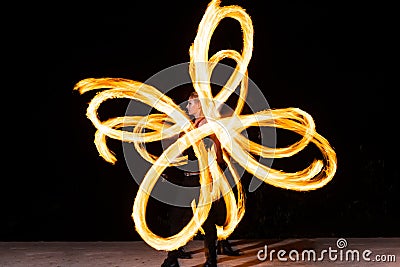 sexy woman artist perform fiery twirly trails by spinning flaming pois during fire performance Stock Photo