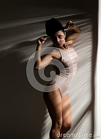 woman in a beige swimsuit and black hat in a shadow stripe Stock Photo