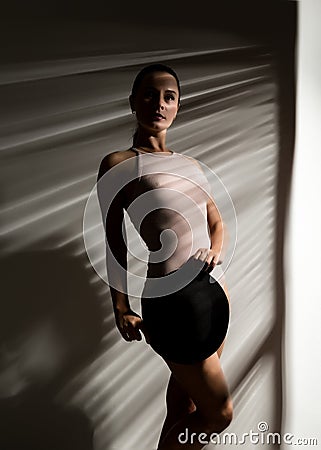 woman in a beige swimsuit and black hat in a shadow stripe Stock Photo