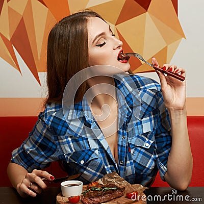 woman biting piece of steak impaled on fork Stock Photo