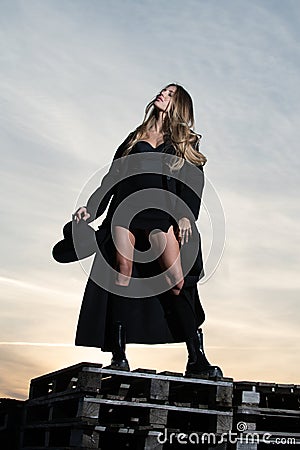 Sexy woman in black fashion coat, hat and black shoes boots. Stylish fashion woman posing outdoor. Attractive young Stock Photo