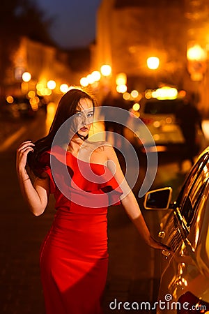 woman at the car. Hollywood star. Fashionable model of elegant girl at night city street. Stock Photo
