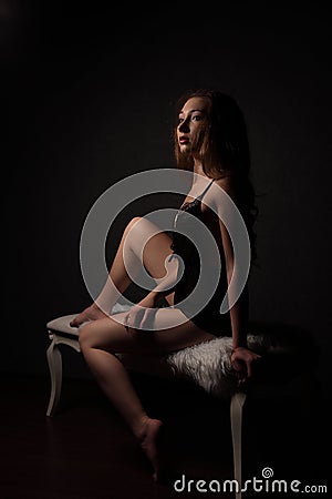 young beautiful brunette woman in sensual black lingerie, sitting on bench. Stock Photo