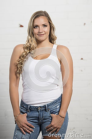 Sexy young blonde woman poses in white tank top and ripped jeans Stock Photo