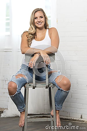 Sexy young blonde woman poses in white tank top and ripped jeans Stock Photo