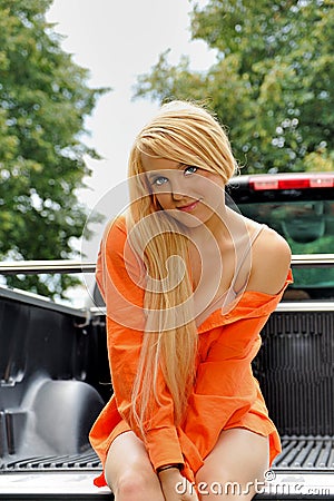 young country woman sitting in back of truck Stock Photo