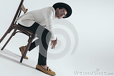 sexy young man holding elbows on knees and sitting on wooden chair Stock Photo