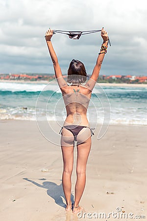 young woman without bra on the tropical beach of Bali island. Bikini girl freedom concept. Indonesia. Stock Photo