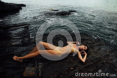 young woman lies on a rock ocean shore. Beautiful girl on stony background Stock Photo