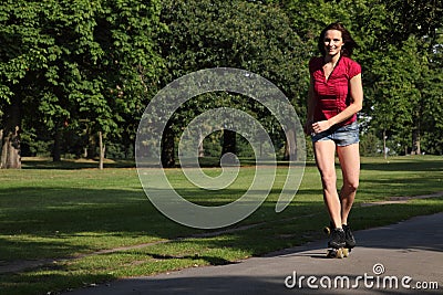 young woman roller skating in park sunshine Stock Photo