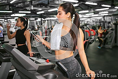 young woman stand on running track and hold phone. She looks at it and smile. Asian young women stand on machine Stock Photo