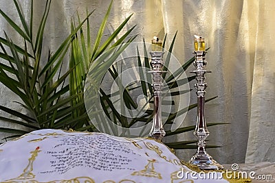 Shabbat table with olive oil candles burning on silver candlesticks and challah cover Stock Photo