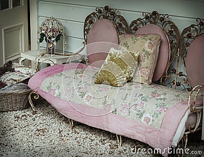A shabby-chic wrought iron sofa sits against an old wooden house Stock Photo