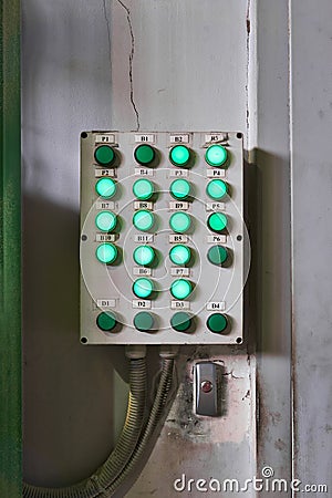 Shabby control panel for some industrial processes with luminous buttons on the wall in the workshop Stock Photo