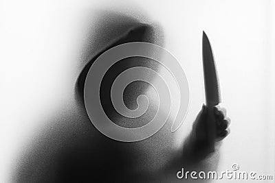 Shadow blur of horror man in jacket with hood knife in his hand. Stock Photo