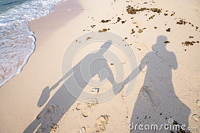 Shadow couple holding hands and Abstract sand of beach and soft wave background Stock Photo