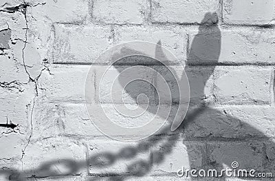 Shadow of hands with chains on a brick wall. Stock Photo