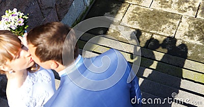 Shadow of kissing young married couple on stone embankment Stock Photo