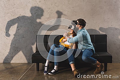 Shadow of man holding knife and scared couple in virtual reality headset Stock Photo