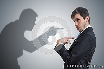 Shadow of man is pointing and blaming businessman. Conscience concept. Stock Photo