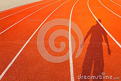 Shadow of man who show extend the arms on red running track Stock Photo