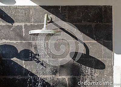 Shadow of an outside shower head on a basalt stone wall, Bali Stock Photo
