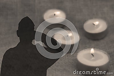 Shadow of a soldier Soldier Israel IDF with salutes on grey background with burning funeral candles. Image for Memorial day Stock Photo