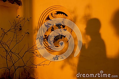 Shadows of praying monk on temple wall in sunlight. Stock Photo