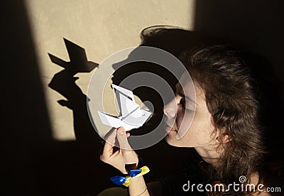 Shadows on wall from a paper dove of peace and a woman`s face. Stop the war in Ukraine Stock Photo