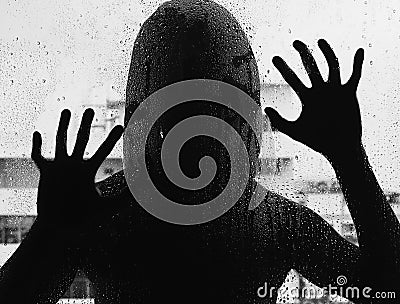 Shadowy figure with a knife behind glass Stock Photo